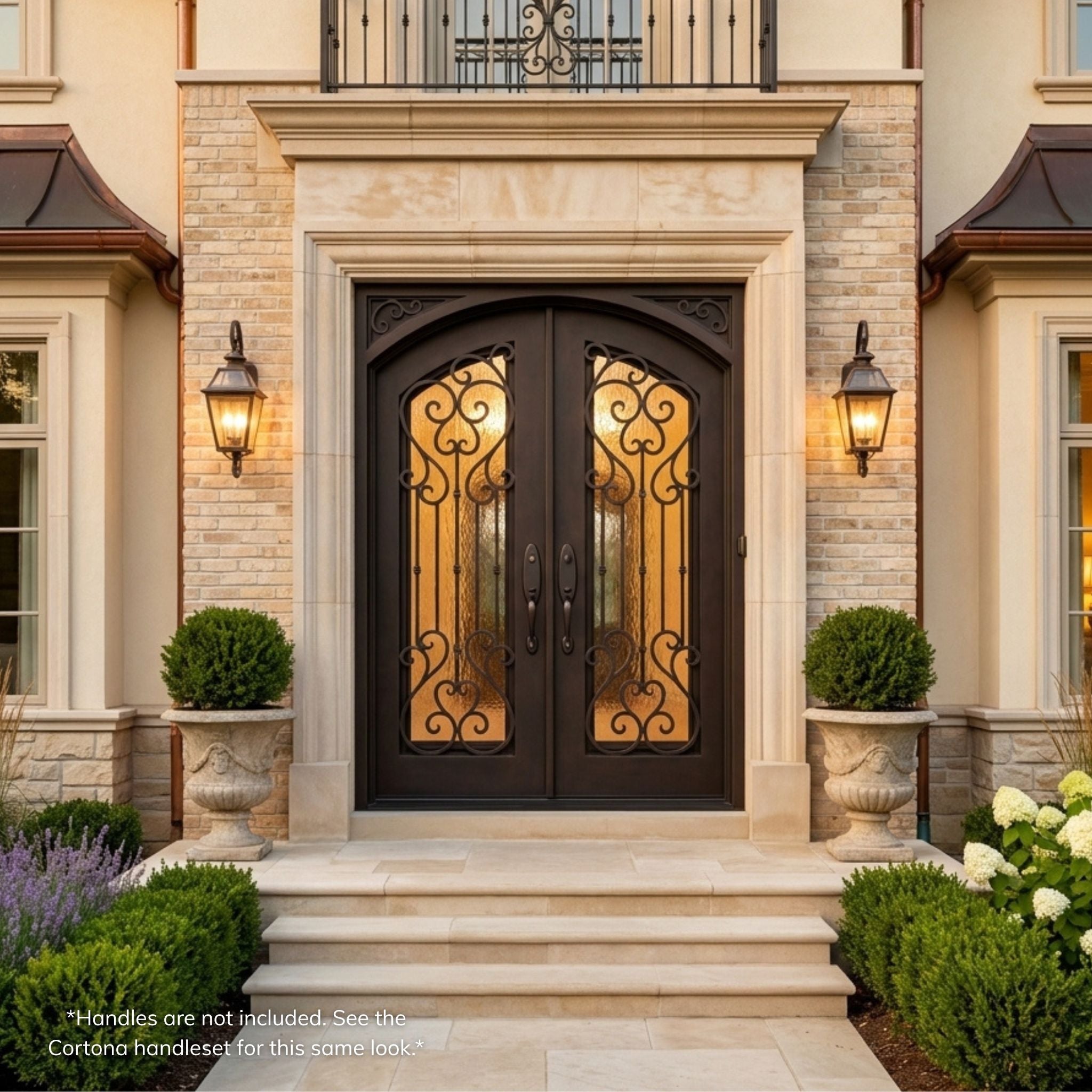 Anastasia double iron entry door, dark oil rubbed bronze finish with vertical scrollwork, Flemish glass panels and scalloped corner accents, installed on a stone and brick home exterior