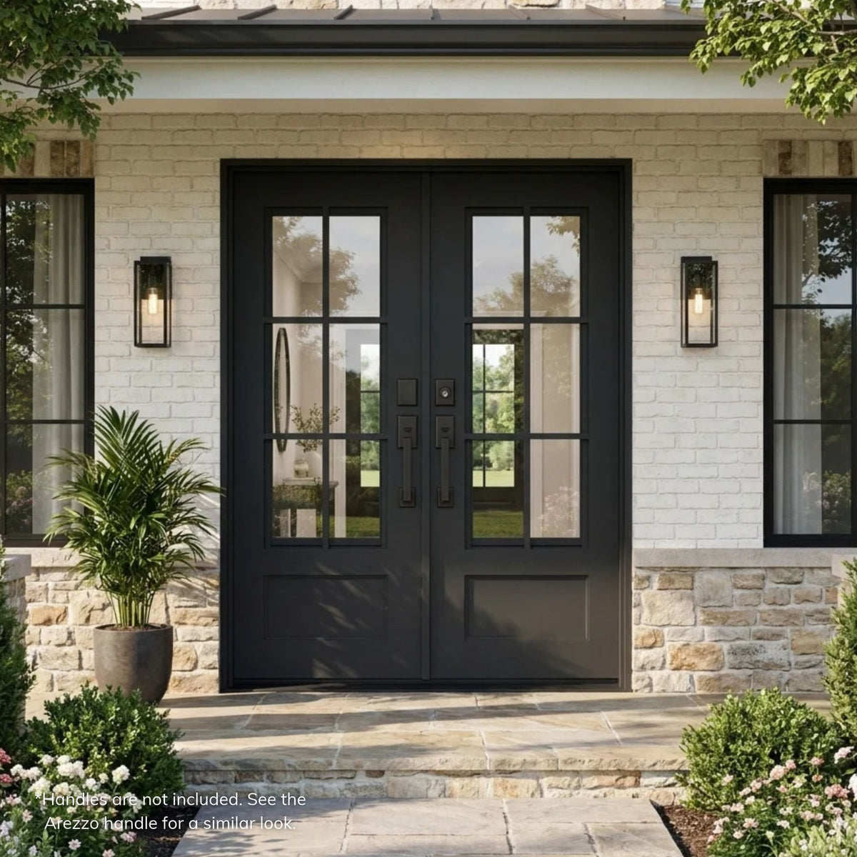Artigiano thermal break wrought iron double door in black with 6-lite clear glass grids over raised bottom panels, installed on a white brick and stone farmhouse-style home