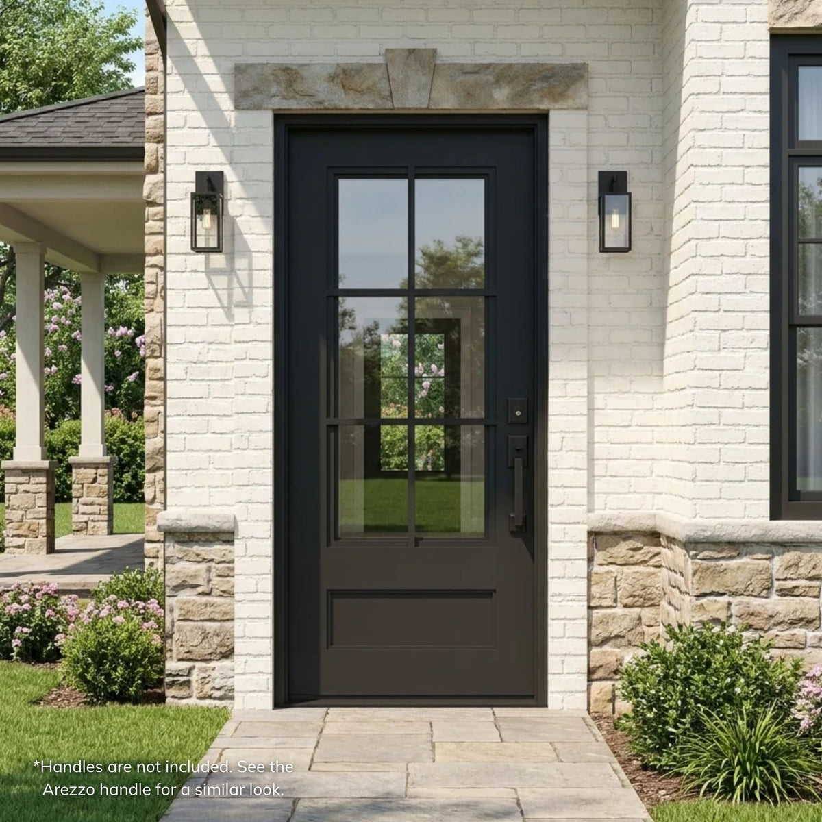 Artigiano black wrought iron single entry door with 6-lite clear glass grid over a raised bottom panel, installed on a painted white brick home with a stone keystone header and stone wainscot