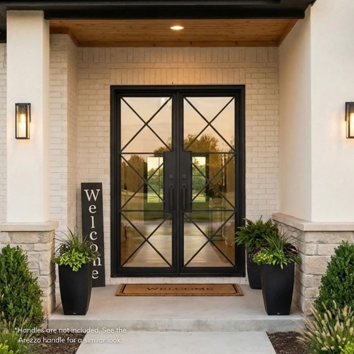 Bella black wrought iron double entry door with full-length clear glass and stacked X-pattern ironwork, set in a recessed white brick entry on a modern farmhouse home