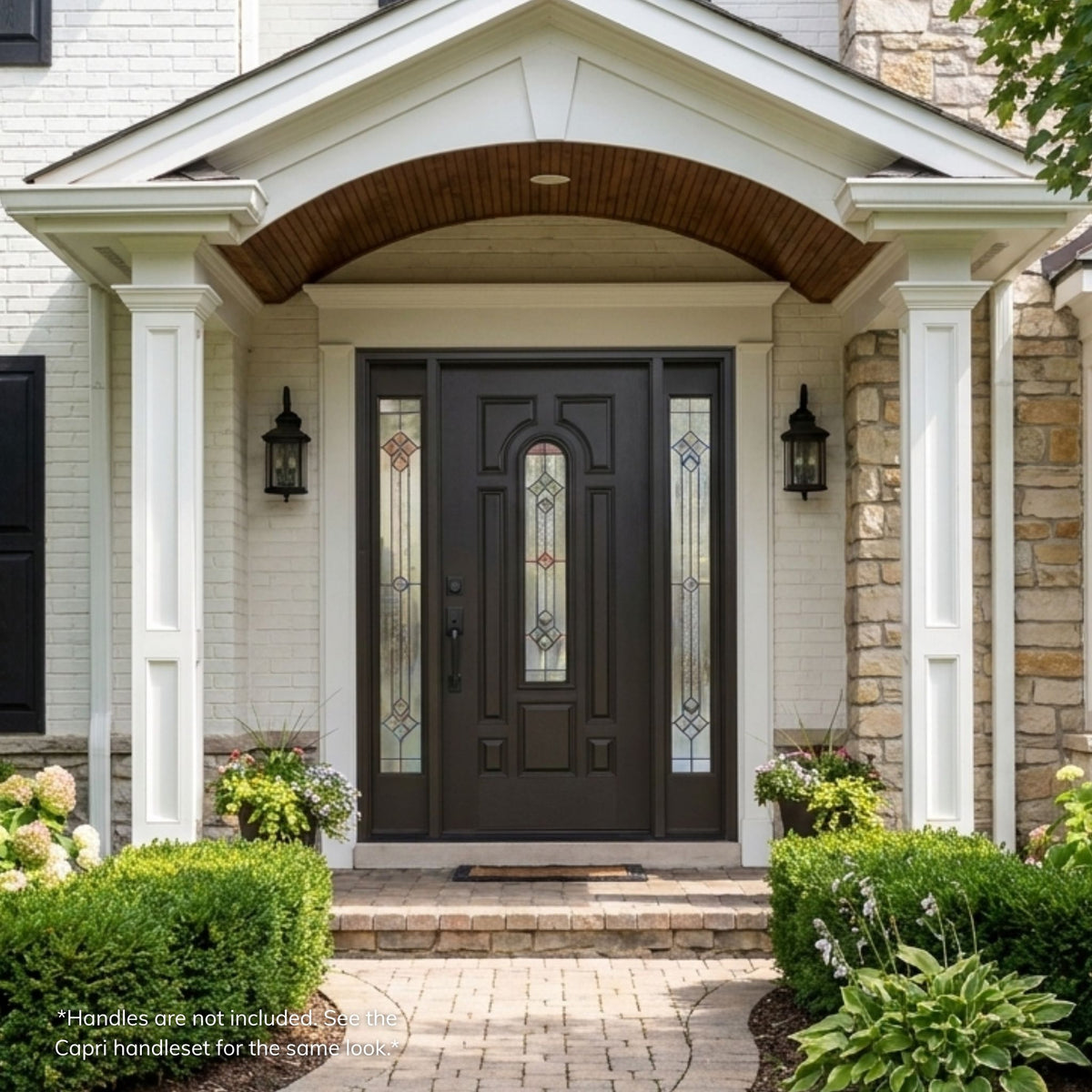 Durban fiberglass single entry door in a dark bronze finish with an arched decorative glass panel featuring a multi-colored diamond geometric pattern, flanked by matching sidelites, installed on a stone and brick home.