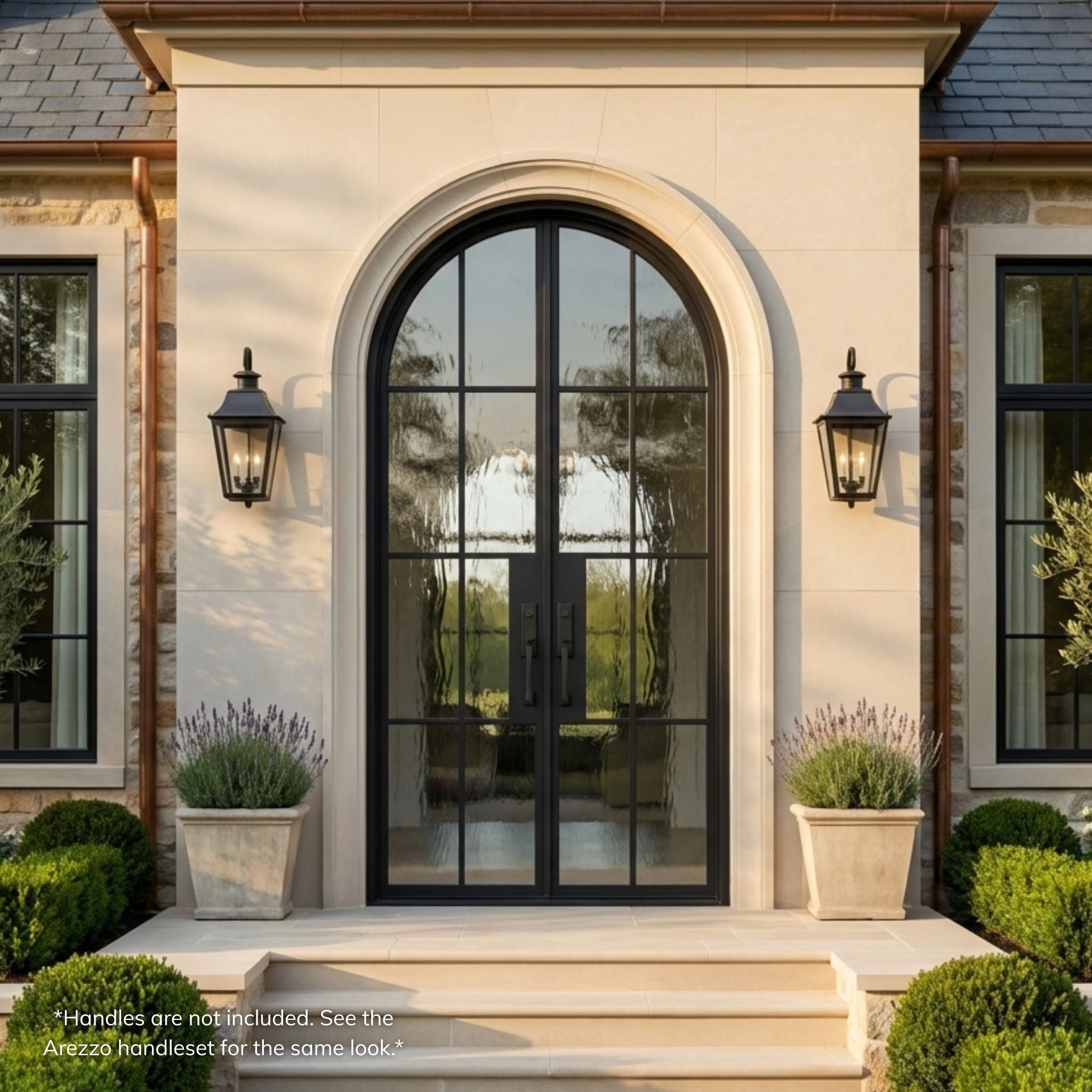 French steel 8-lite arch top double entry door, matte black finish with Flemish glass, installed on a stone home exterior