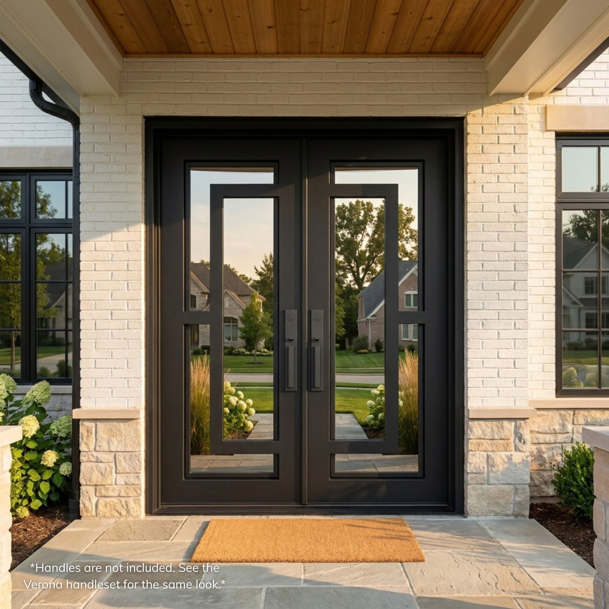 Henry wrought iron double entry door, matte black finish with full-view mirror glass panels and modern geometric grille pattern, installed on a white brick home exterior with covered entry