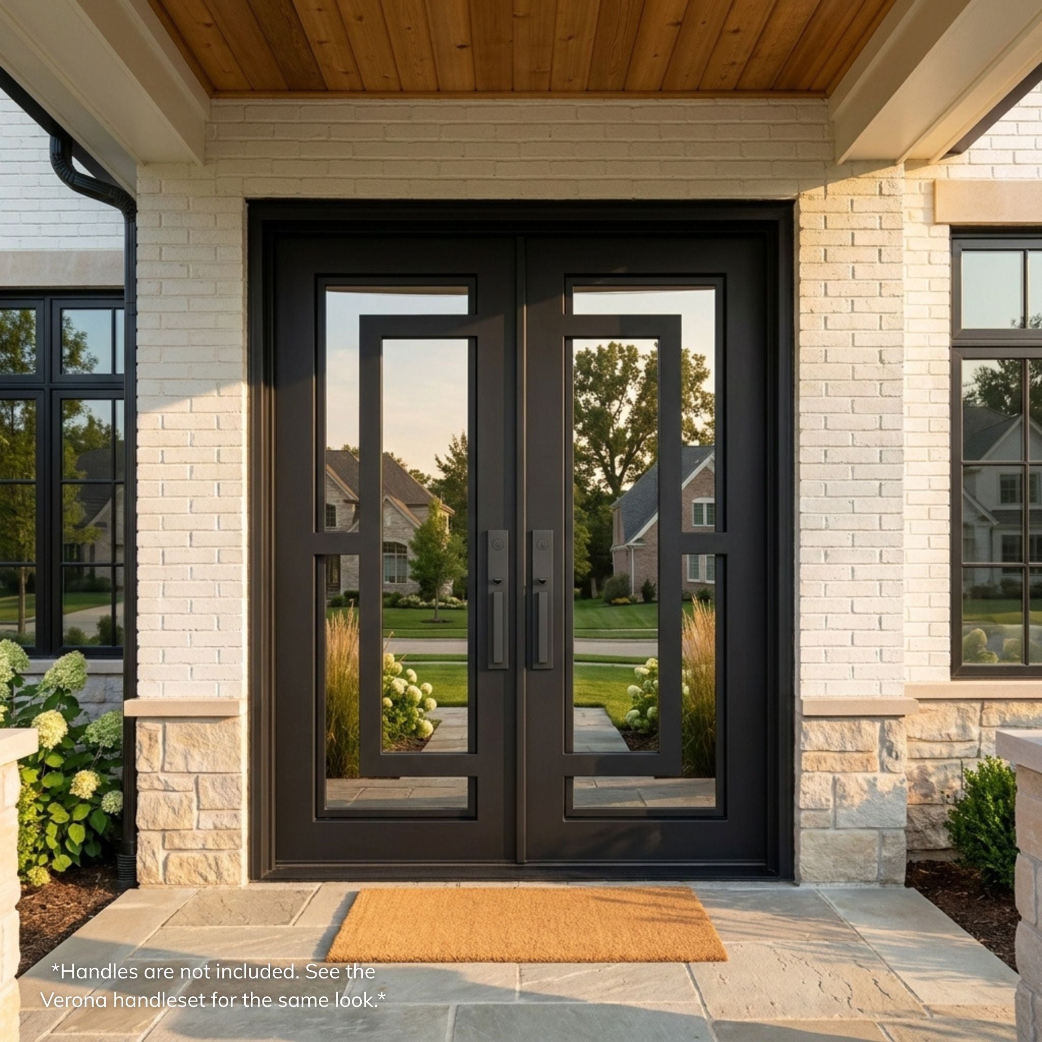 Henry wrought iron double entry door, matte black finish with full-view mirror glass panels and modern geometric grille pattern, installed on a white brick home exterior with covered entry