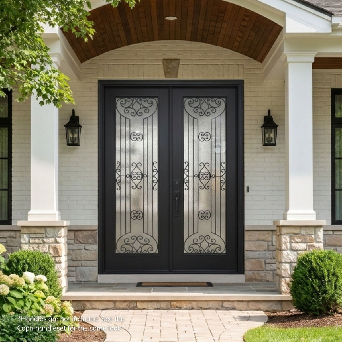 Jupiter fiberglass double entry door in a matte black finish with full-lite decorative glass panels featuring an arched scrollwork design, installed on a stone and brick home.