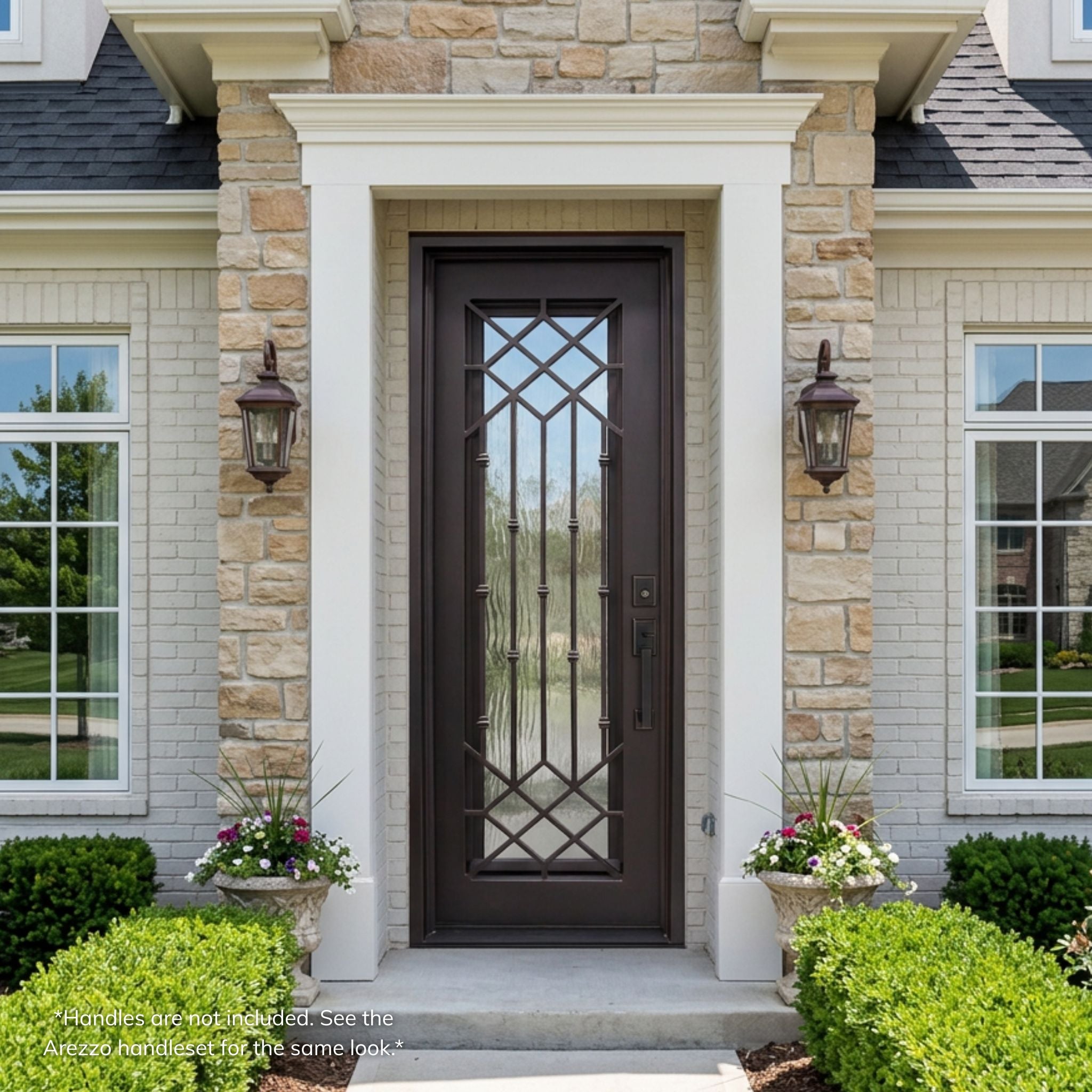 Lux wrought iron full-view single entry door, dark bronze finish with geometric lattice pattern and Flemish glass, installed on a stone home exterior with lantern sconces